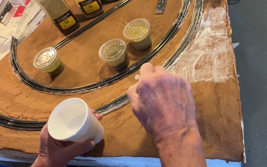applying ground cover for model railroad mountain